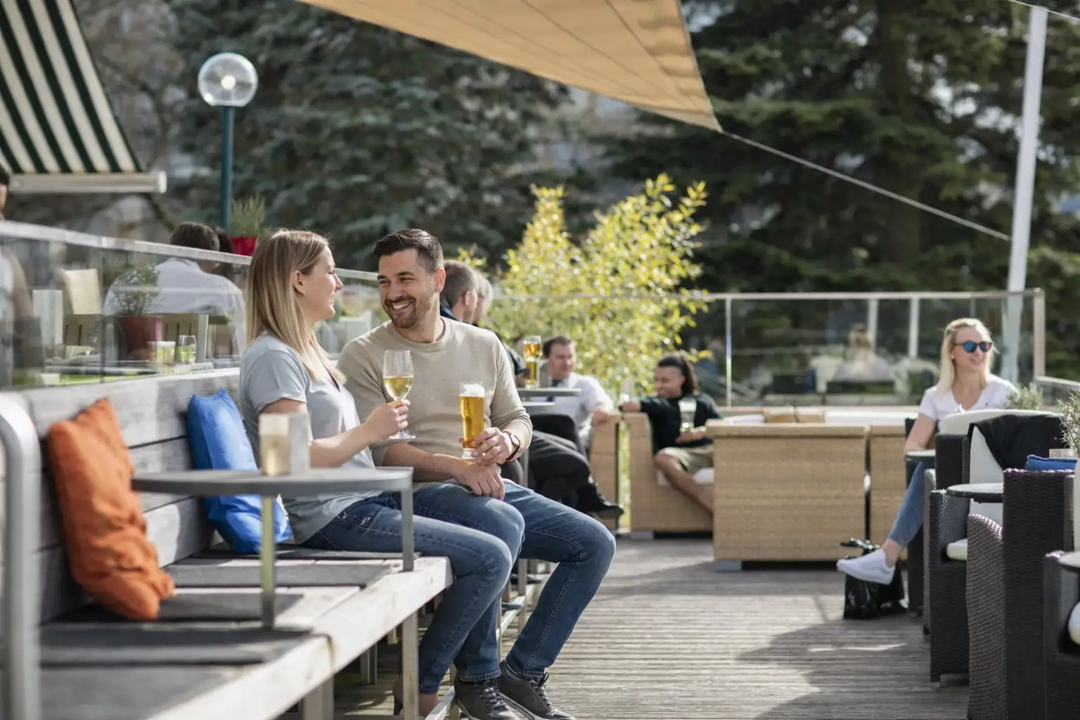 Zwei Gläser Bier auf der Terrasse im Restaurant, umgeben von Gästen und Pflanzen.