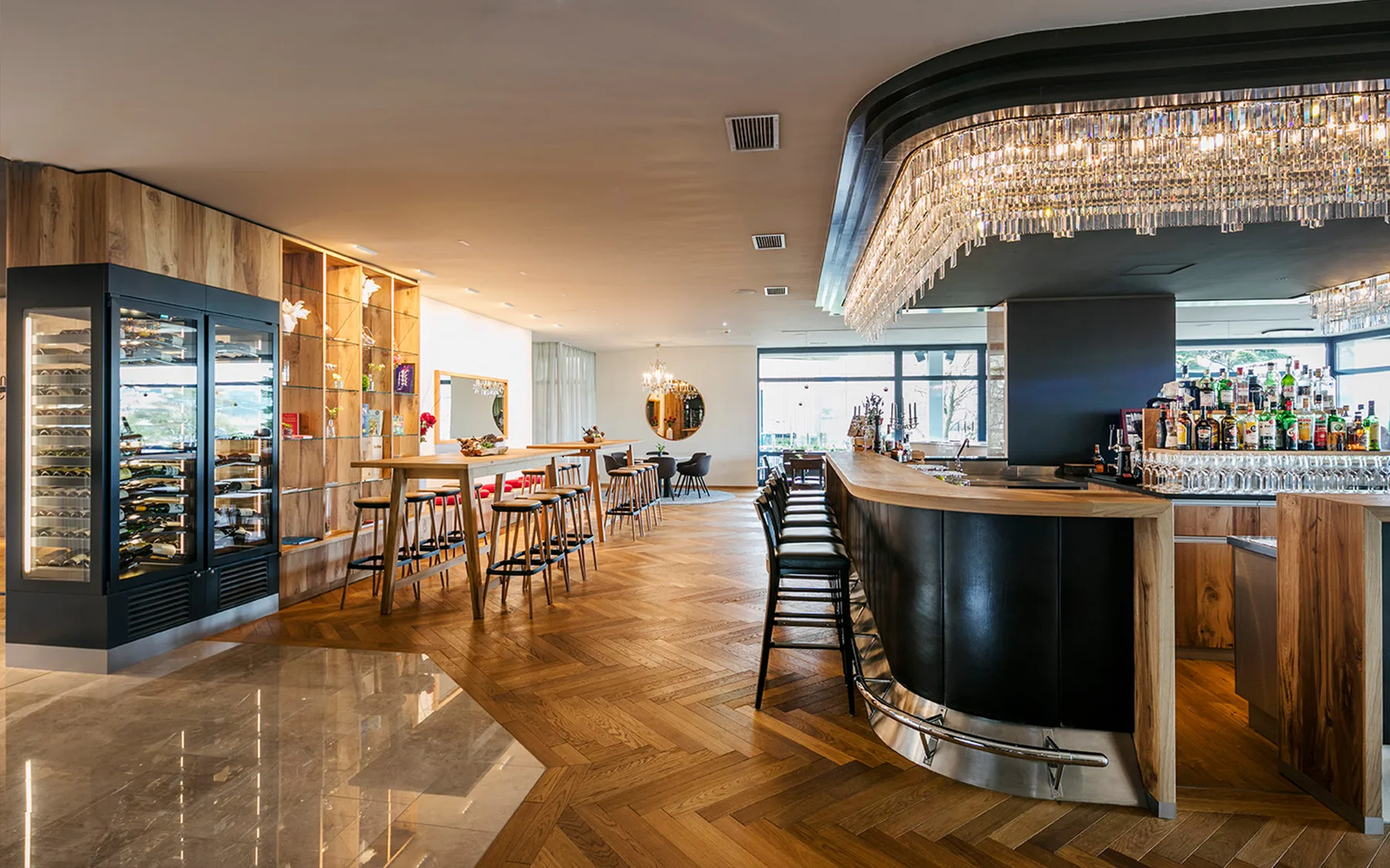 A view of a modern bar with wooden shelves and elegant lighting.