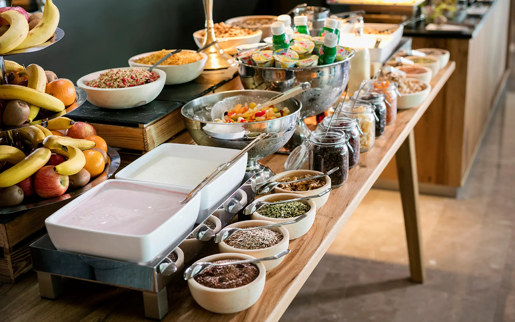 Ein reichhaltiges Frühstücksbuffet mit frischem Obst, Joghurt und verschiedenen Toppings.