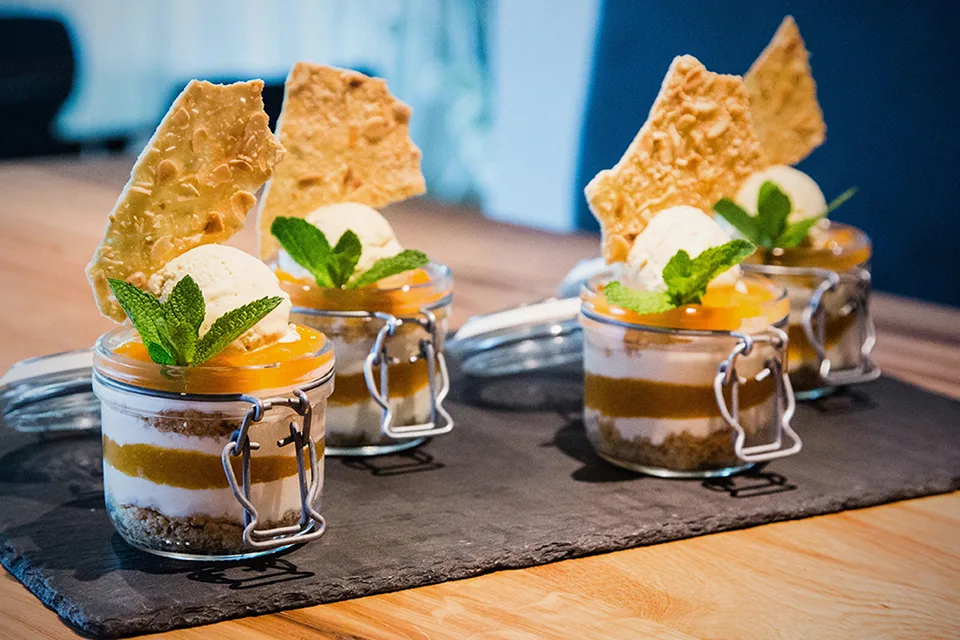 Three jars of dessert with yogurt, caramel layers, and ice cream, garnished with mint.
