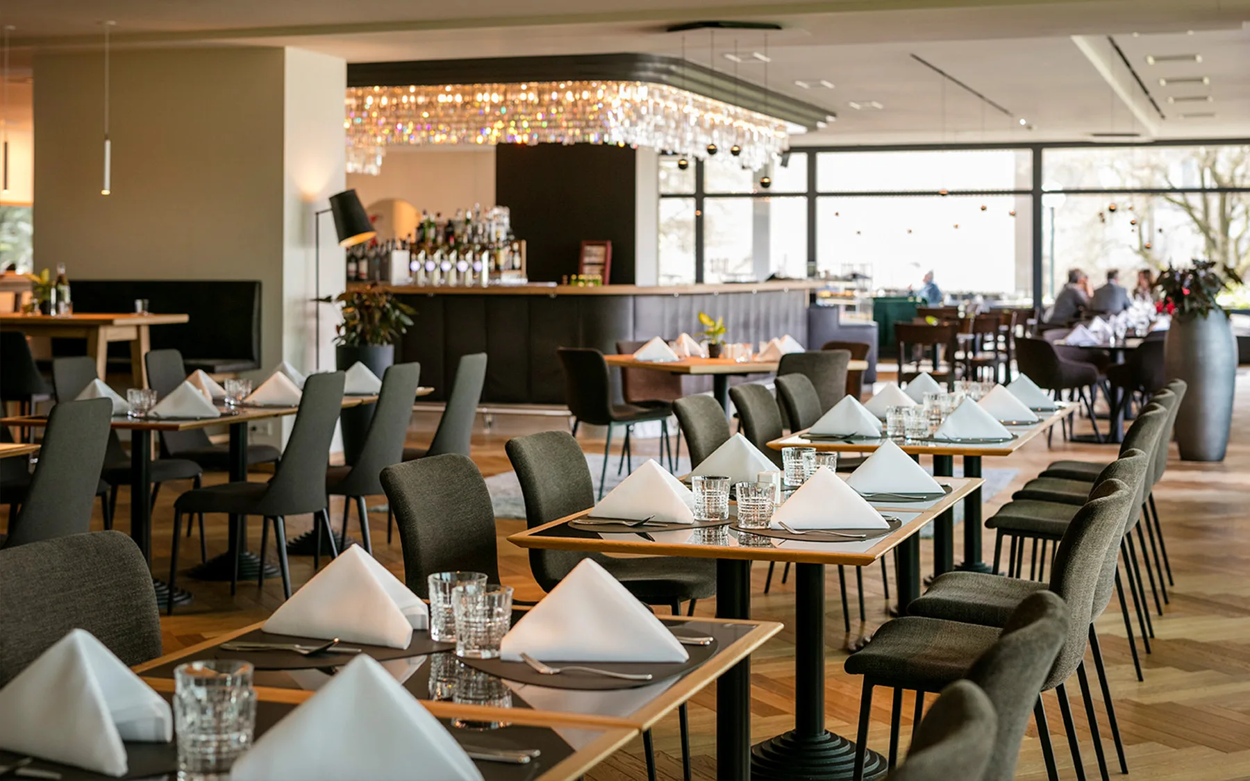 Interior view of an elegant restaurant with set tables and a bar in the background.