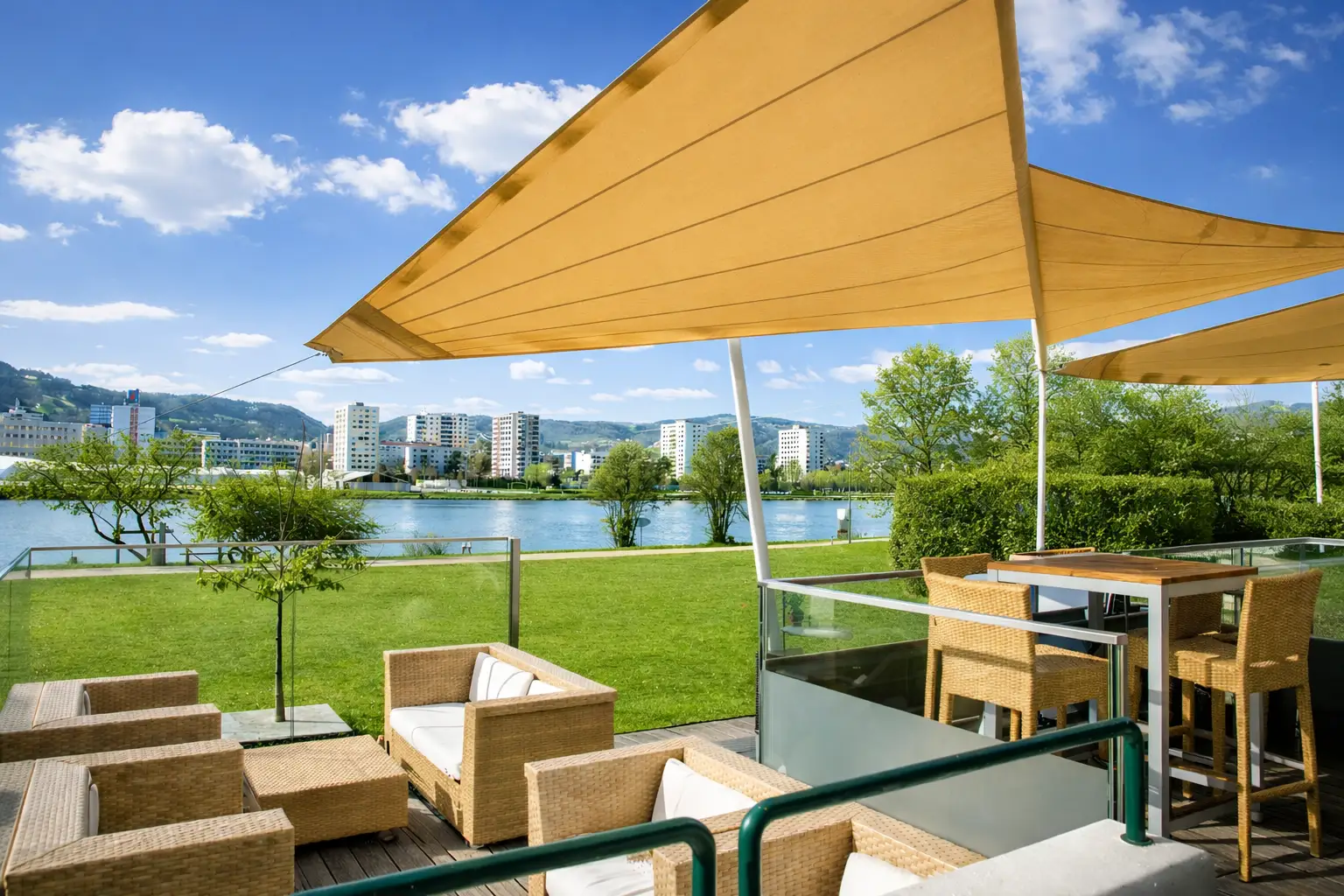 Gemütliche Terrasse mit Blick auf den Fluss und moderne Architektur im Hintergrund.