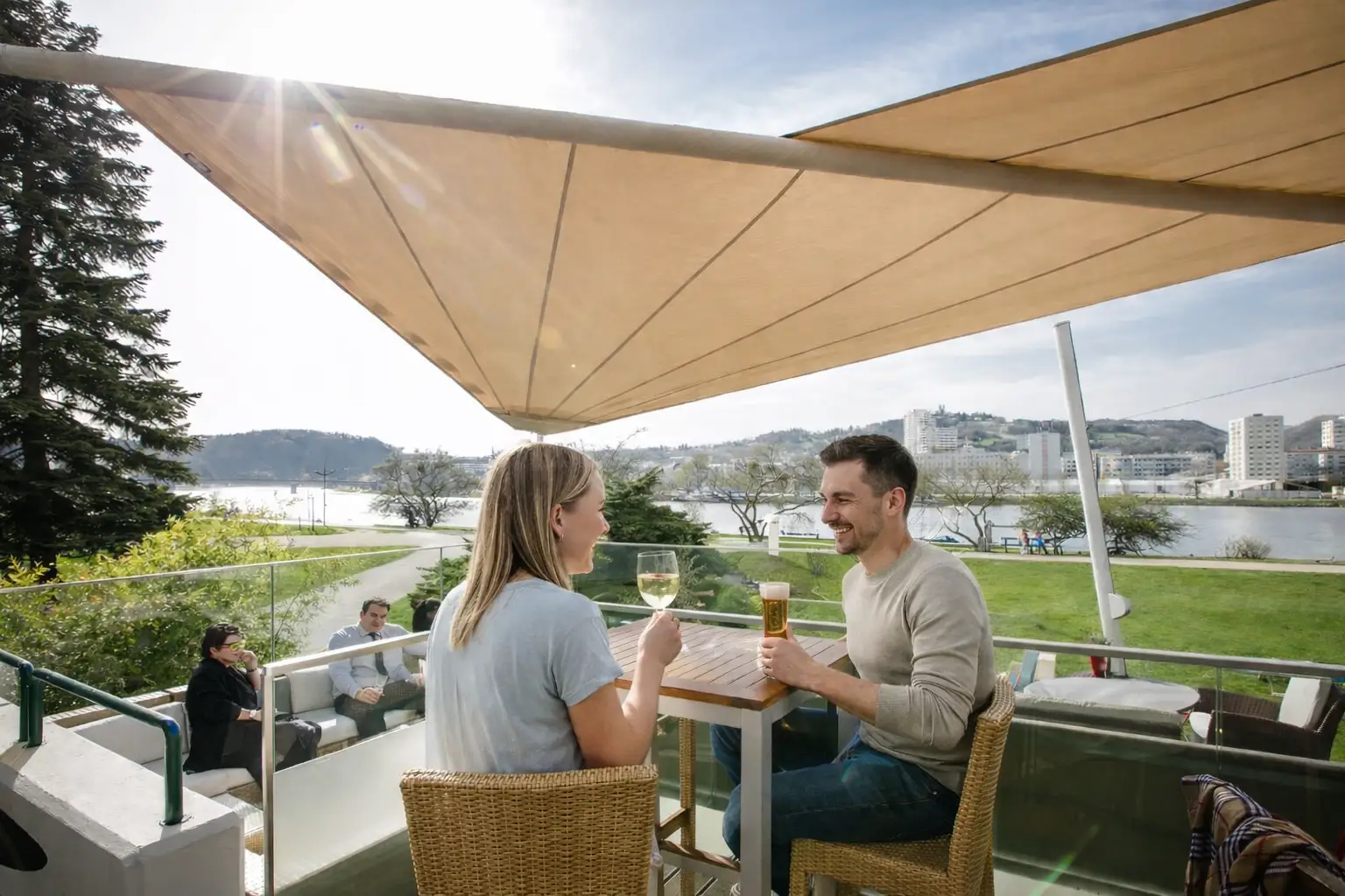 Pärchen mit Wein und Bier auf der Terrasse des Restaurants mit Blick auf den Fluss.